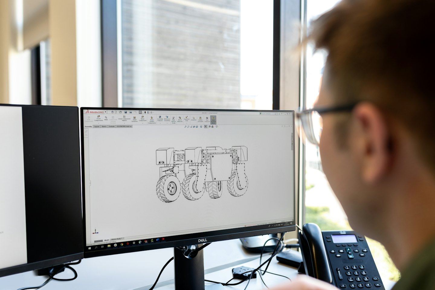 Mann konstruiert einen Roboterrahmen am Computer.