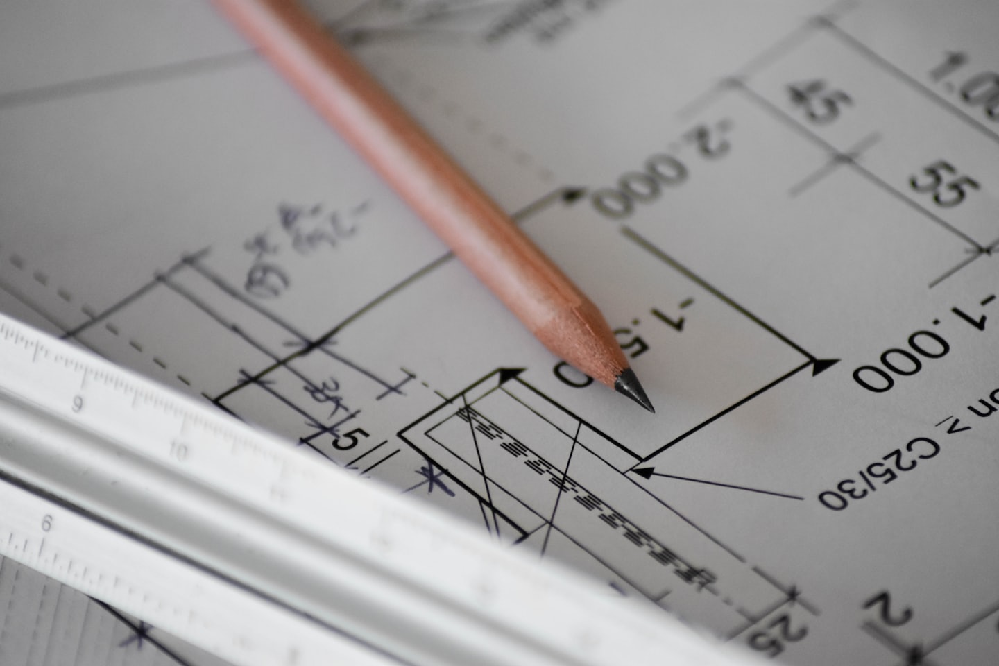 Holzstift und Architektenmaßstab auf einem Bauplan.