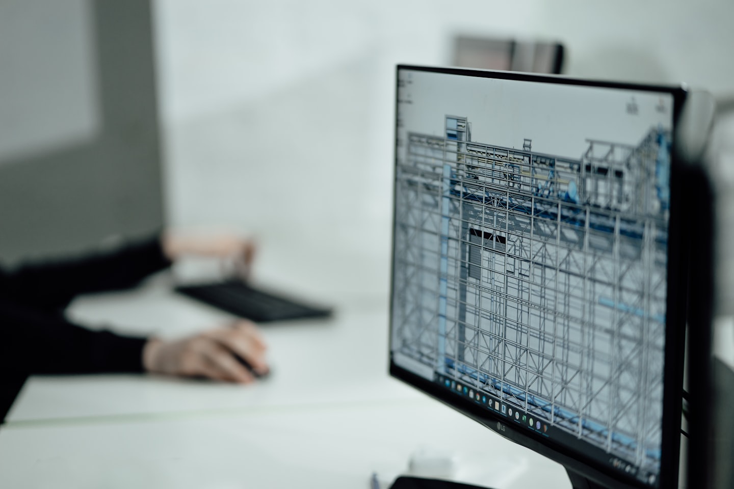 Computermonitor zeigt 3D-Drahtgittermodell mit Händen auf der Tastatur.
