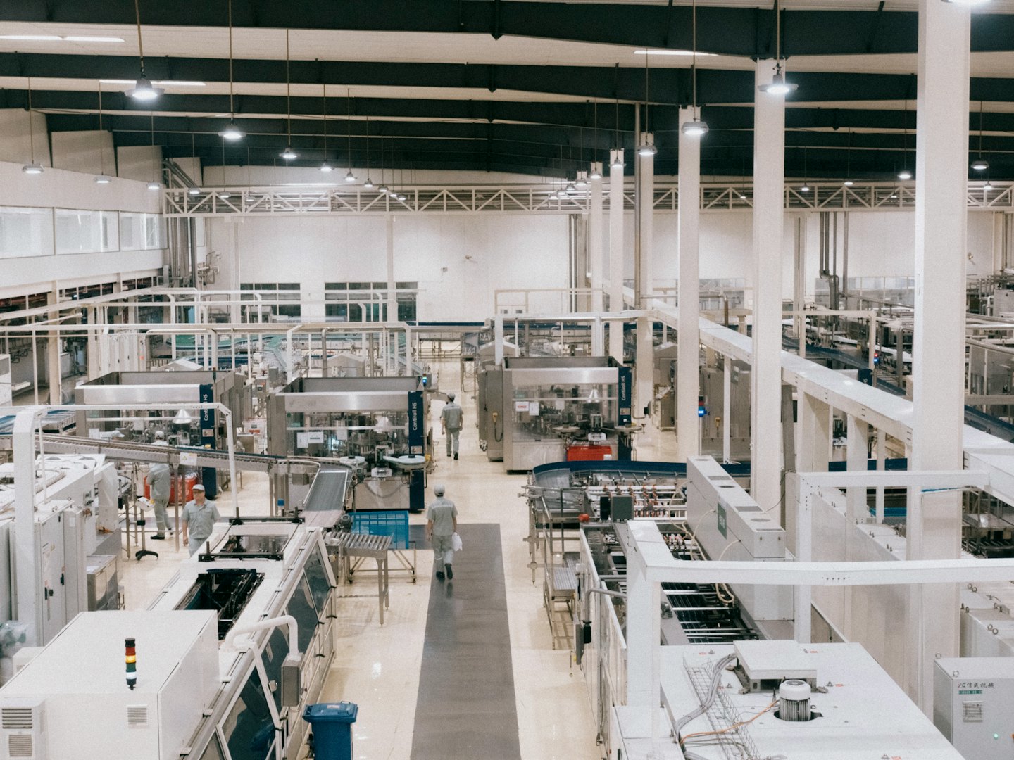 Arbeiter bewegen sich zwischen automatisierten Maschinen auf einer Produktionslinie.